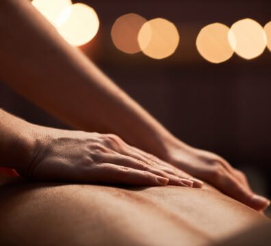 Closeup image of masseuse applying light strokes when applying oil on back of client