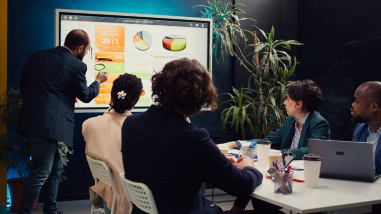 Sales manager creates a presentation to pitch in a new strategy for development, using interactive board to make his staff members understand the objectives. Business planning meeting.