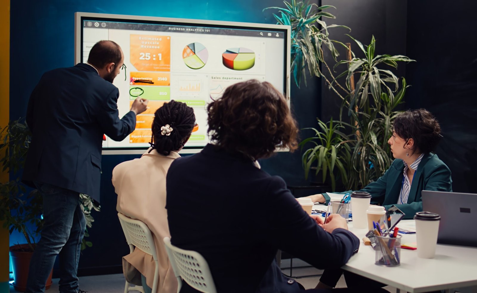 Sales manager creates a presentation to pitch in a new strategy for development, using interactive board to make his staff members understand the objectives. Business planning meeting.