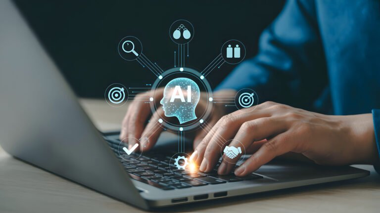 A close-up shot shows hands typing on a laptop keyboard. A digital illustration of a human head with the letters "AI" inside it is displayed above the keyboard, surrounded by various technology-related icons such as a magnifying glass, targets, a checkmark, a gear, and a handshake. The icons are connected by lines, forming a network around the AI head. The overall color scheme is predominantly blue and white, with a subtle glow emanating from the keyboard.
